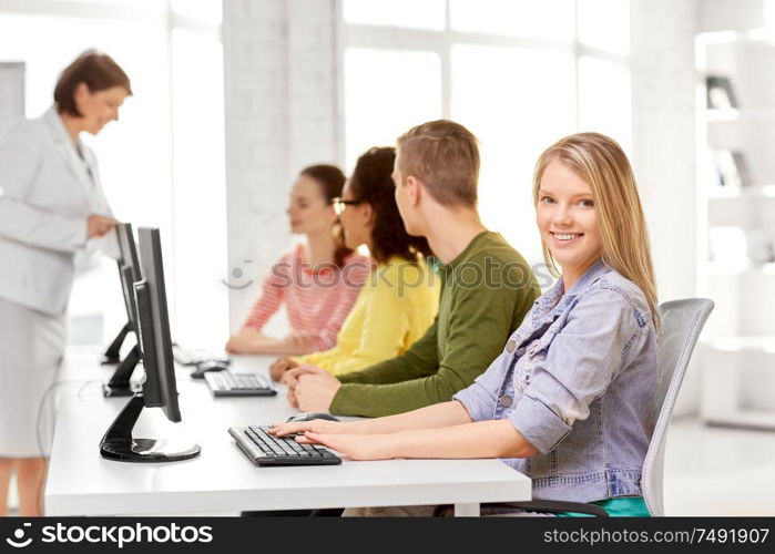 education, technology and learning concept - group of happy international high school students or classmates in computer class. happy high school students in computer class