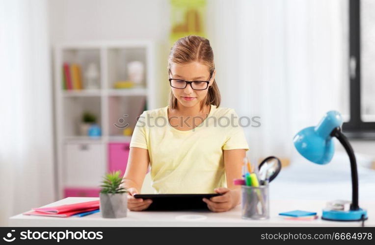 education, technology and learning concept - student girl with tablet computer doing homework at home. student girl with tablet computer doing homework