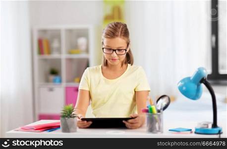 education, technology and learning concept - student girl with tablet computer doing homework at home. student girl with tablet computer doing homework