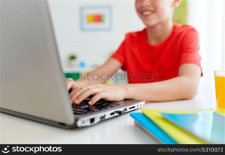 education, technology and people concept - close up of smiling student boy typing on laptop computer at home. student boy typing on laptop computer at home