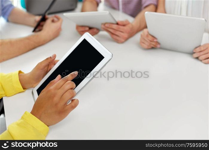 education, technology and people concept - group of international high school students or classmates with tablet pc computers at table. group of high school students with tablet pc