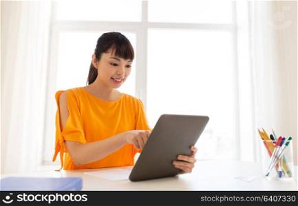 education, technology and people concept - happy smiling asian student girl with tablet pc computer learning at home. asian student girl with tablet pc learning at home