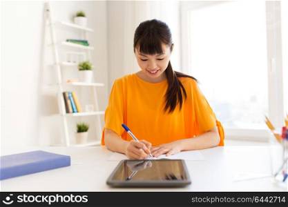 education, technology and people concept - happy smiling asian student girl with tablet pc computer learning at home. asian student girl with tablet pc learning at home