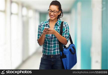 education, technology and people concept - smiling female african american student in eyeglasses with smartphone and bag