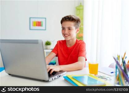 education, technology and people concept - smiling student boy typing on laptop computer at home. student boy typing on laptop computer at home
