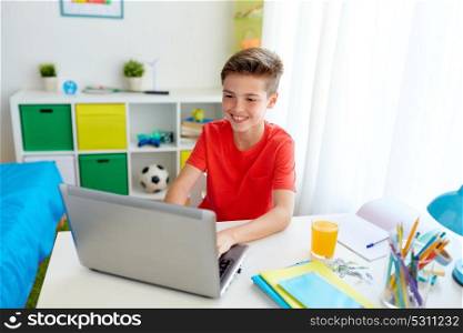 education, technology and people concept - smiling student boy typing on laptop computer at home. student boy typing on laptop computer at home