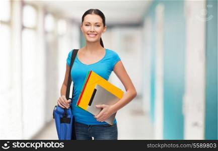 education, technology and people concept - smiling student with bag, folders and tablet pc computer standing at school corridor