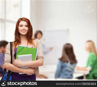 education, technology and people concept - smiling student with bag, folders and tablet pc computer standing in class
