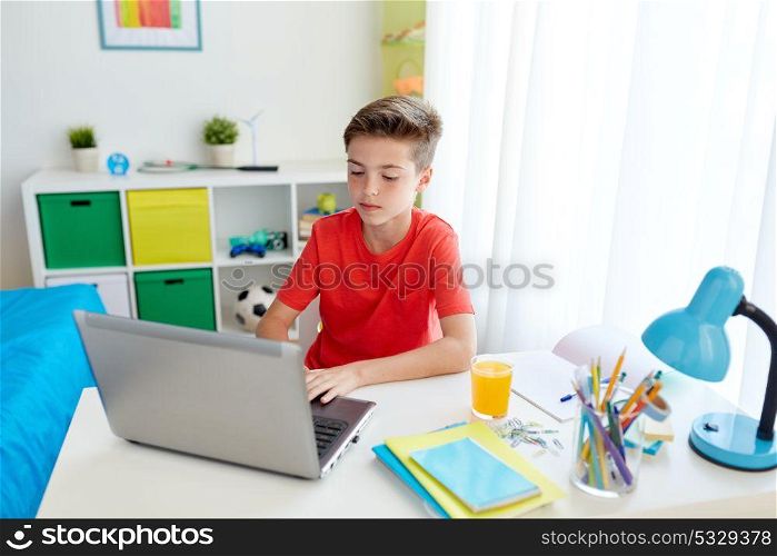 education, technology and people concept - student boy typing on laptop computer at home. student boy typing on laptop computer at home