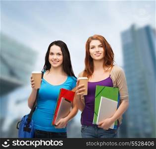education, technology and people concept - two smiling students with bag, folders, tablet pc and takeaway coffee standing