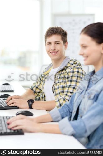 education, technology and school concept - smiling boy with girl in computer class at school