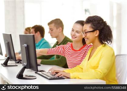 education, technology and school concept - smiling female students in computer class at school
