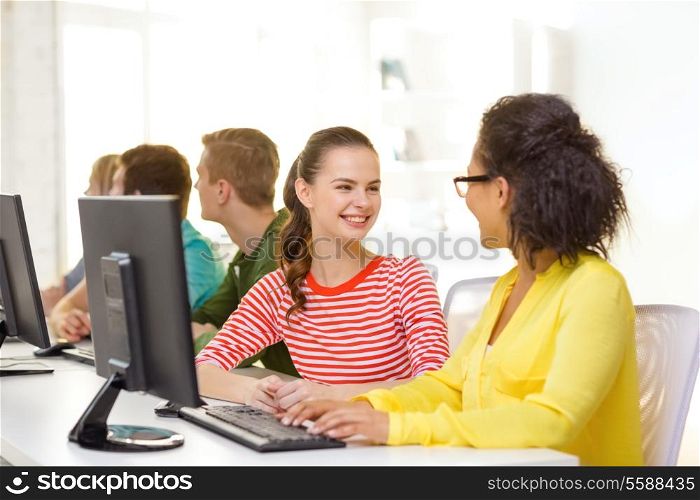 education, technology and school concept - smiling female students in computer class at school having discussion