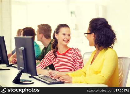education, technology and school concept - smiling female students in computer class at school having discussion