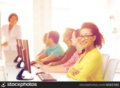 education, technology and school concept - smiling male student with classmates in computer class with teacher