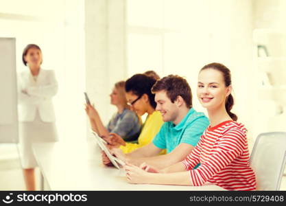 education, technology and school concept - smiling male student with classmates in computer class with teacher