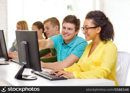 education, technology and school concept - smiling students in computer class at school