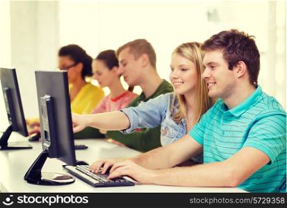 education, technology and school concept - smiling students in computer class at school