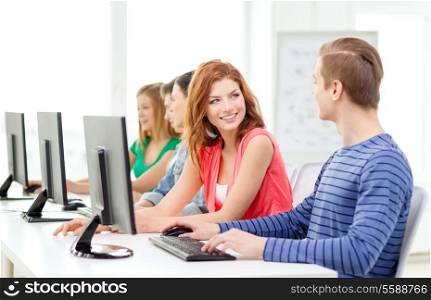 education, technology and school concept - smiling students in computer class at school having discussion