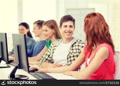 education, technology and school concept - smiling students in computer class at school having discussion