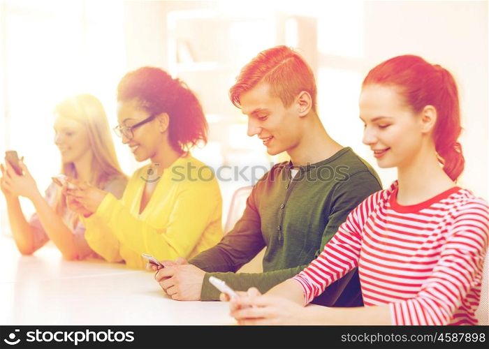 education, technology and school concept - smiling students with smartphones at school