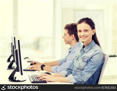 education, technology and school concept - two smiling students in computer class