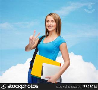 education, technology, gesture and people concept - smiling female student with bag, tablet pc computer and folders showing victory gesture