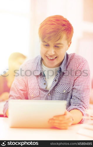 education, technology, internet and school concept - smiling teenage boy student with tablet pc computer at school