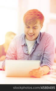 education, technology, internet and school concept - smiling teenage boy student with tablet pc computer at school