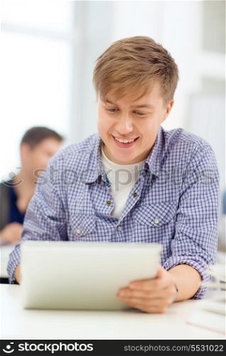 education, technology, internet and school concept - smiling teenage boy student with tablet pc computer at school