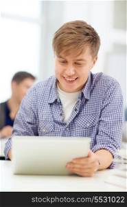 education, technology, internet and school concept - smiling teenage boy student with tablet pc computer at school