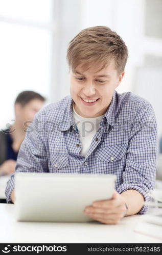 education, technology, internet and school concept - smiling teenage boy student with tablet pc computer at school