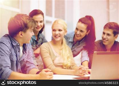education, technology, school and internet concept - group of smiling students with laptop and at school