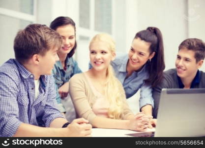 education, technology, school and internet concept - group of smiling students with laptop and at school