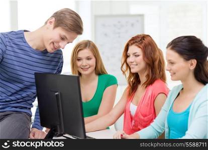 education, technology, school and people concept - group of smiling students having discussion in computer class at school