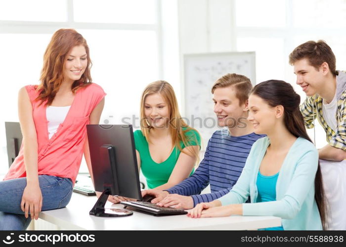 education, technology, school and people concept - group of smiling students having discussion in computer class at school