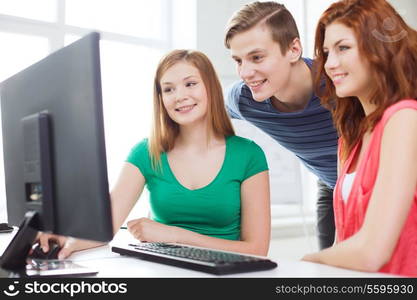 education, technology, school and people concept - group of smiling students having discussion in computer class at school