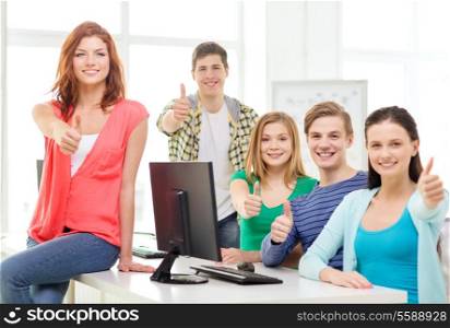 education, technology, school and people concept - group of smiling students showing thumbs up in computer class at school