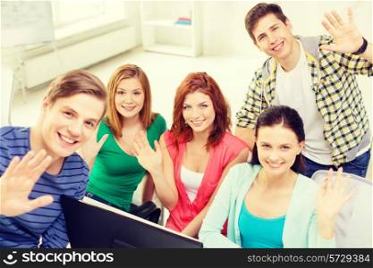 education, technology, school and people concept - group of smiling students waving hands in computer class at school