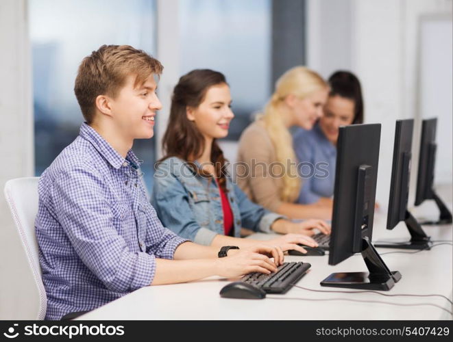 education, techology and internet concept - group of smiling students looking at computer monitor at school