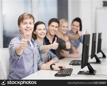 education, techology and internet concept - group of smiling students with computer monitor showing thumbs up at school