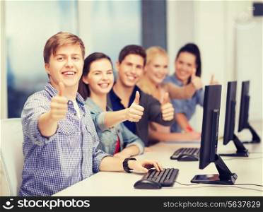 education, techology and internet concept - group of smiling students with computer monitor showing thumbs up at school