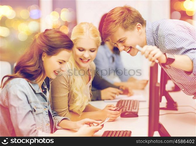 education, techology and internet concept - group of smiling students with computer monitor and smartphones