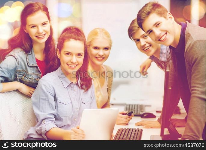 education, techology and internet concept - group of smiling students with computer monitor and tablet pc