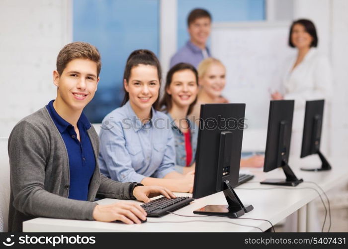 education, techology and internet concept - group of smiling students with computer monitor at school