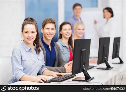 education, techology and internet concept - group of smiling students with computer monitor at school