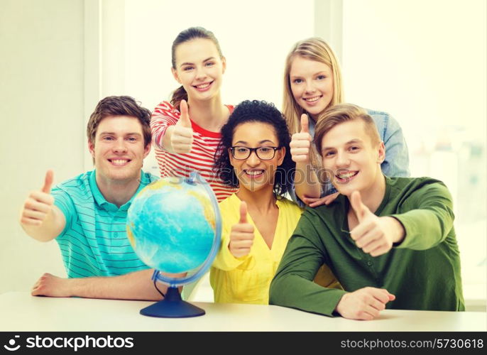 education, travel and geography concept - five smiling student with earth globe at school showing thumbs up