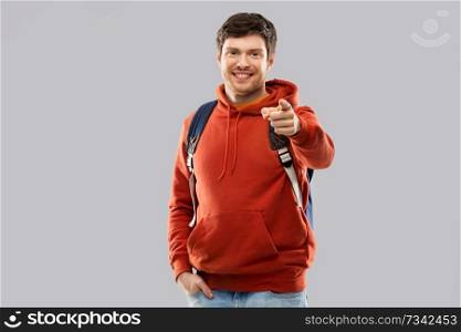 education, travel and people concept - young man or student with school bag or backpack over grey background. young man or student with school bag or backpack