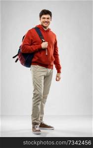 education, travel and people concept - young man or student with school bag or backpack over grey background. young man or student with school bag or backpack