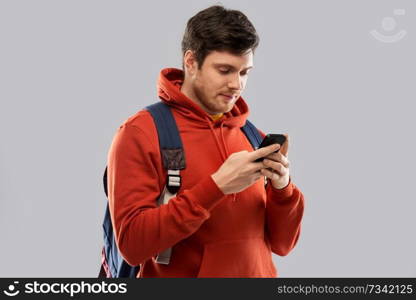 education, travel and technology concept - young man or student with smartphone and school bag or backpack over grey background. man or student with smartphone and school bag